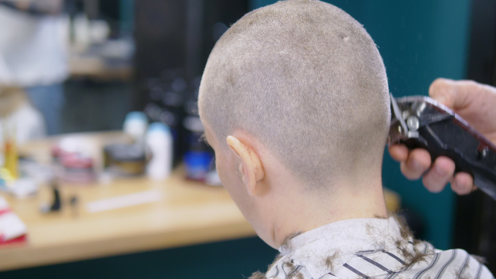 A father shaves his daughter's head after she was caught bullying a classmate with cancer.
